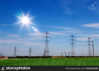 Landscape of Power Line of the Electric Wires at the Blue Sky at the Green Grass with Bright Sun
