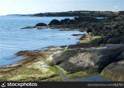 Landscape of rocky seashore with blue calm waters in summer day as natural background