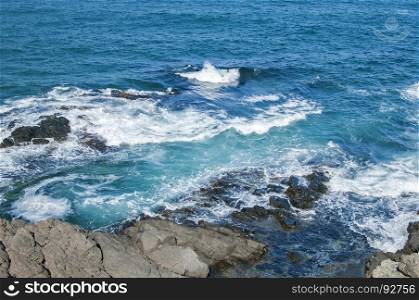 Landscape of rocky seashore with blue calm waters in sunny summer day as natural background