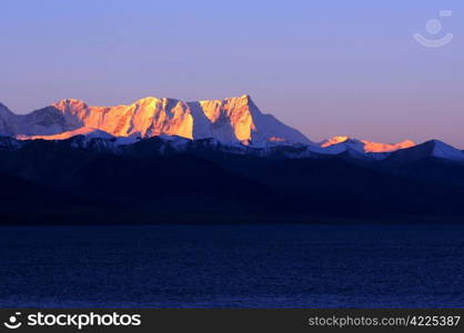 Landscape of snow-capped mountains at lakeside in Tibet at sunrise