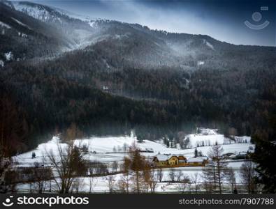 Landscape of snowstorm over Austrian Alps grown with forest