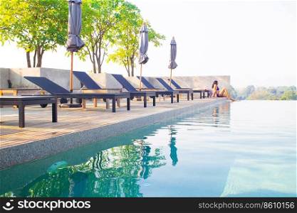 Landscape of swimming pool on the roof top with asian woman relaxing