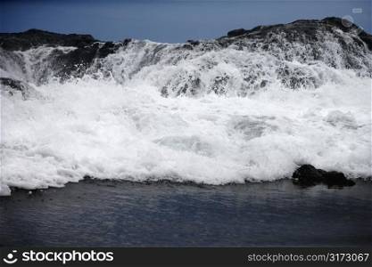 Landscape of waves crashing into rocky Maui Hawaii coast.