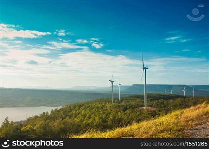 Landscape of windmill with green forest and clear blue sky over the mountain.