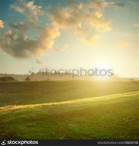 landscape on sunset - green field under sky and clouds