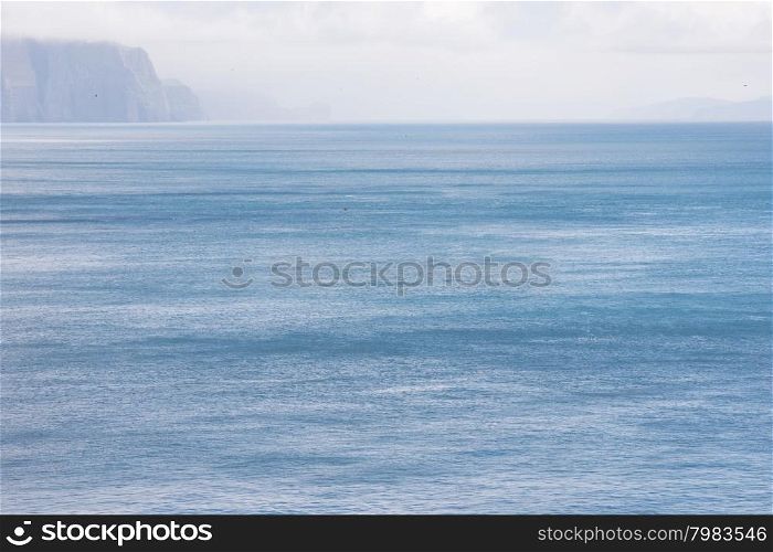 Landscape on the Faroe Islands. Typical landscape on the Faroe Islands as seen from Mykines with blue ocean and clouds