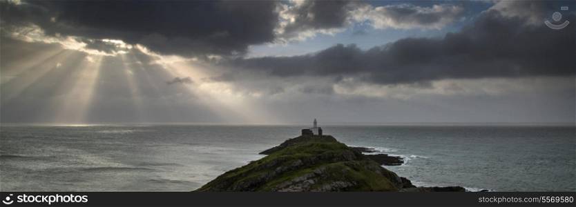 Landscape panorama of Mumbles lighthouse in Wales with sun beams over sea