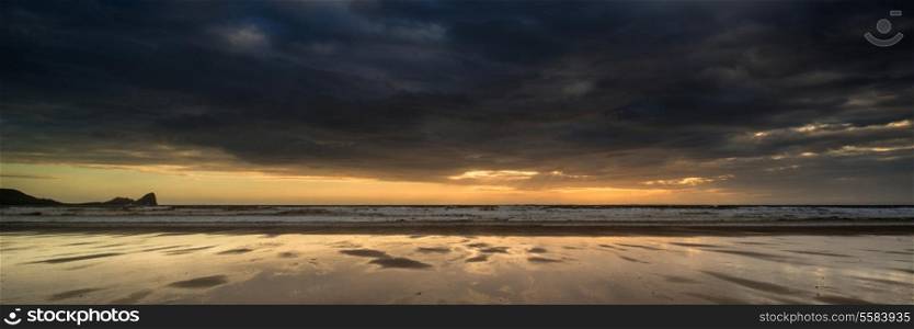 Landscape panorama Rhosilli Bay beach at sunset with dramatic sky