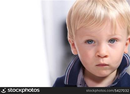 Landscape portrait of a serious little boy with blonde hair and blue eyes