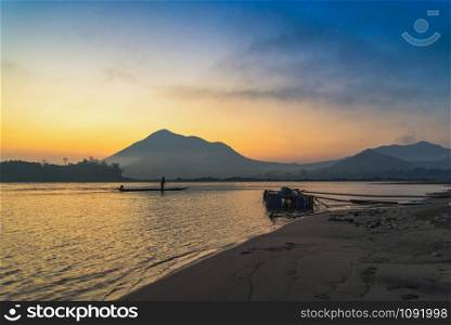 Landscape river beach fisherman on fishing boat beautiful sunrise and colorful sky on mountain background in Mekong River Asia
