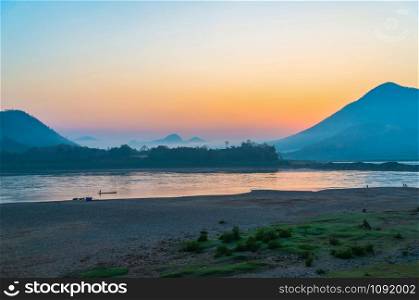 Landscape river beach fisherman on fishing boat beautiful sunrise and colorful sky on mountain background in Mekong River Asia