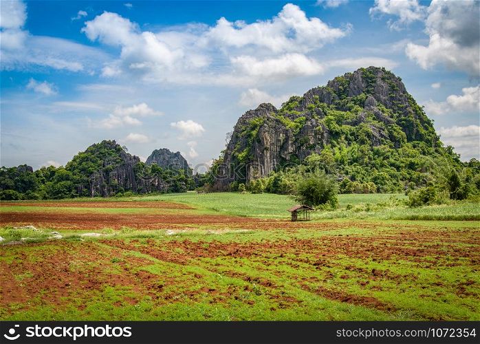Landscape rural fields with plow agricultural farm area for farmer planting and rock mountain blue sky background / begin farming corn field