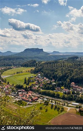 Landscape shot of the mountain called Lilienstein, seen from the lookout point Bastei in Saxon Switzerland, a nature and hiking area in Germany. The small town of Rathen can be seen in the foreground.. The mountain called Lilienstein, seen from the Bastei viewpoint in Saxon Switzerland