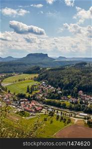 Landscape shot of the mountain called Lilienstein, seen from the lookout point Bastei in Saxon Switzerland, a nature and hiking area in Germany. The small town of Rathen can be seen in the foreground.. The mountain called Lilienstein, seen from the Bastei viewpoint in Saxon Switzerland