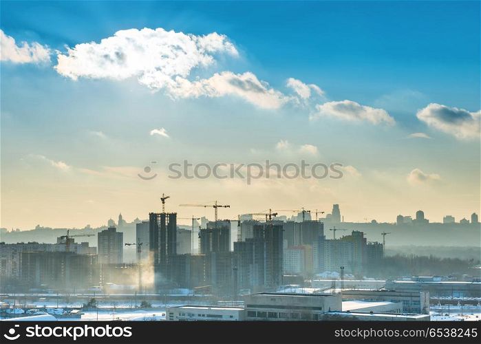 Landscape sunset in the city with blue sky, sun and industrial cranes. Landscape sunset in the city