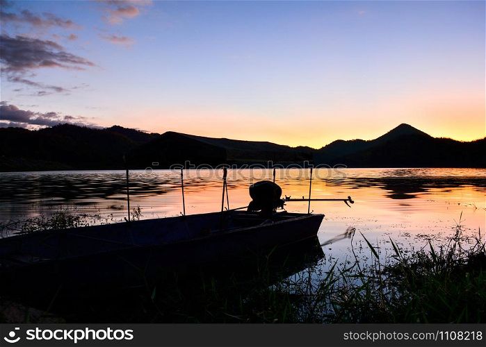 Landscape sunset river with fishing boat and yellow and blue sky twilight beautiful silhouette mountain background