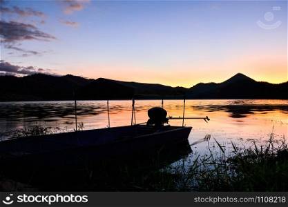 Landscape sunset river with fishing boat and yellow and blue sky twilight beautiful silhouette mountain background