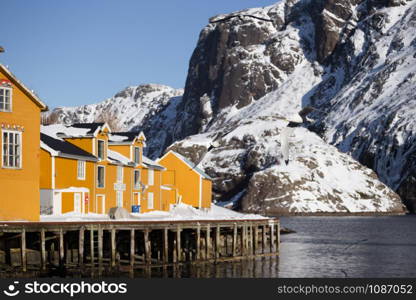 landscape - traditional norwegian wooden house rorbu to stand on the shore of the fjord and mountains in the distance. Norway.