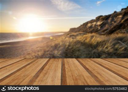 Landscape vibrant sunset over beach and cliffs with aded lens flare effect with wooden planks floor