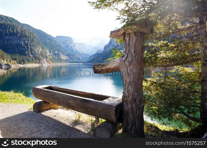 landscape with a beautiful mountain lake with reflection. Autumn. water from the forest wooden water trough at the autumn mountains forest