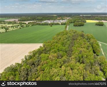 Landscape with a forest, meadows and fields and a small village in the background, aerial view from a height of 100 meters, Germany