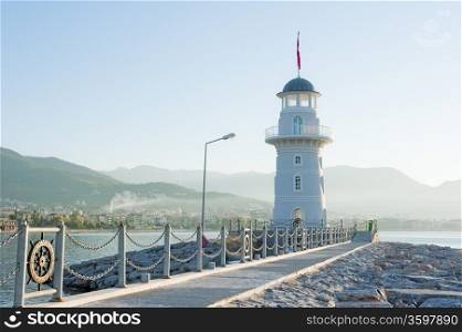 Landscape with a lighthouse in the harbor town of Alanya at dawn.