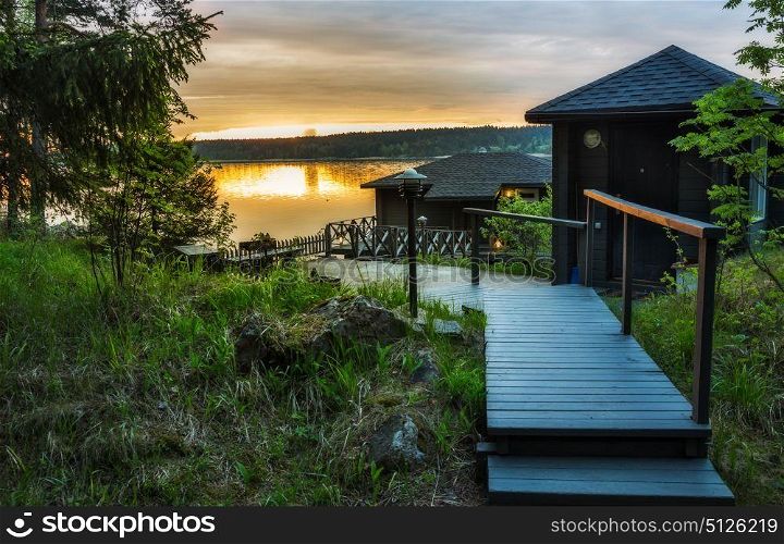 Landscape with a lodge on the lake in Karelia at sunset