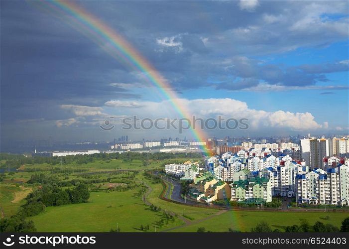Landscape with a rainbow above city and park. Rainbow of city
