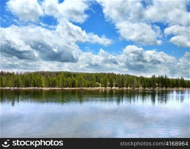 landscape with big lake with forest in high mountains and beautiful sky