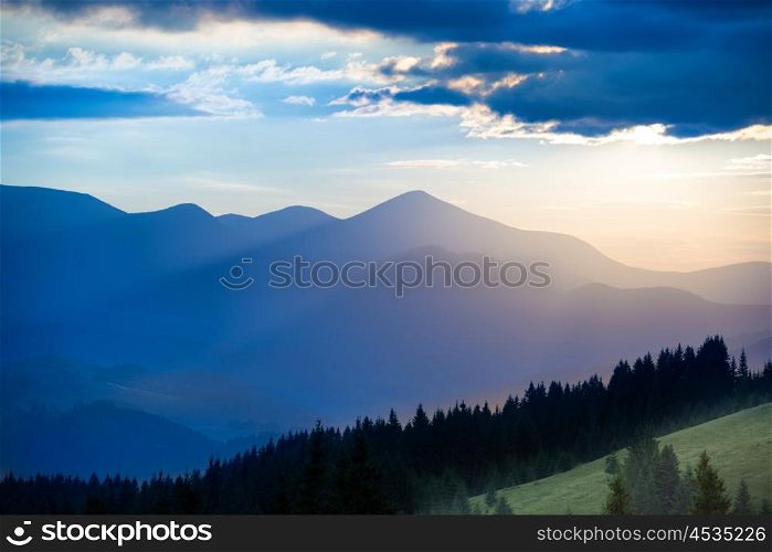 Landscape with blue mountains and forest at sunset