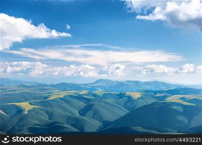 Landscape with blue mountains, forest and white clouds on sky