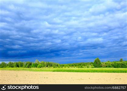 landscape with dark thundercloud clouds under the trees. landscape with dark thundercloud clouds under the forest and land