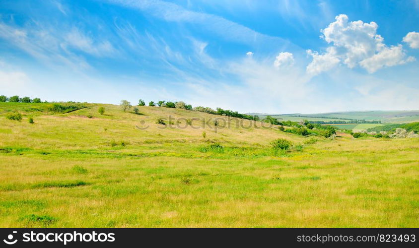 Landscape with hilly field and blue sky. Agricultural landscape.Wide photo.