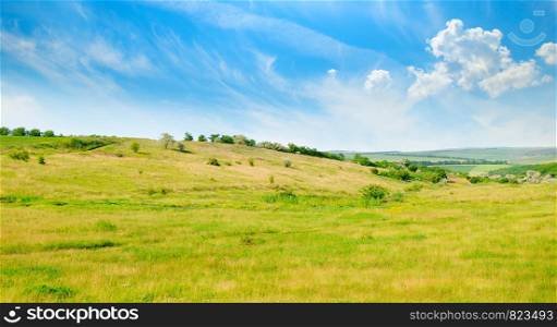 Landscape with hilly field and blue sky. Agricultural landscape.Wide photo.