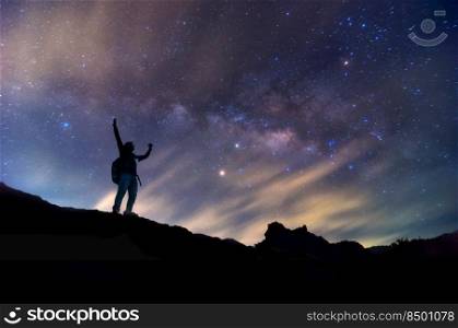 Landscape with Milky Way. Night sky with stars and silhouette of a standing happy man on the mountain, Success or winner, leader concept. High iso with Noise..  leader at night