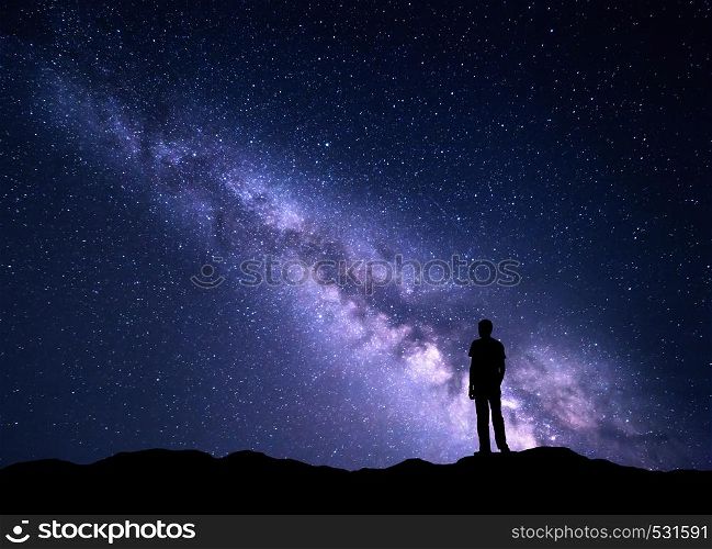 Landscape with purple Milky Way. Night sky with stars and silhouette of a happy man on the mountain. Beautiful Universe. Space background