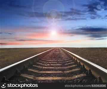 landscape with rails going away into the sunset and evening sun. landscape with railway track going away into the sunset and evening star