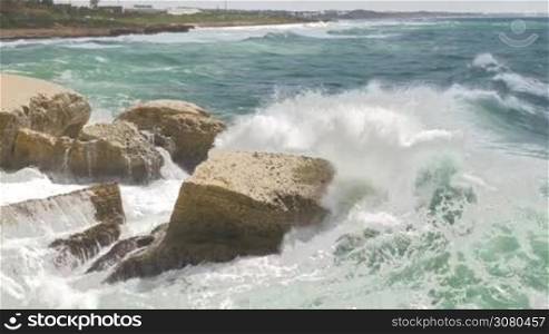 Landscape with Rosh Hanikra coast and strong waves of turquoise sea crushing white chalk rocks
