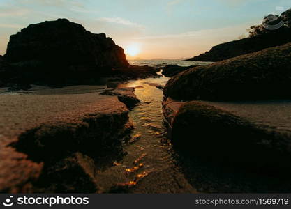 Landscaped shot of the water going through a trail in the sand of the beach