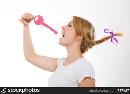 Language barrier concept. Teenage blonde girl with braid hair biting big pink key. Teenage girl with braid biting key