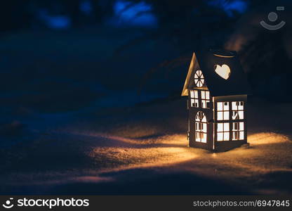 Lantern house with burning candle on snow in the evening. Lantern house with burning candle on snow in the evening.