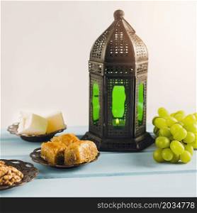 lantern near green grape with baklava turkish delights saucers