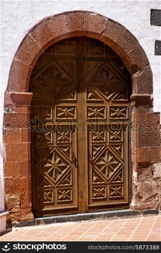 lanzarote spain canarias brass brown knocker in a closed wood church door and white wall abstract &#xA;