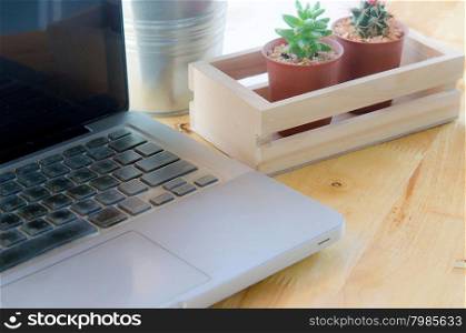 Laptop and cactus in flowerpot on wooden table