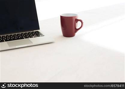 Laptop and coffee cup on floor of office