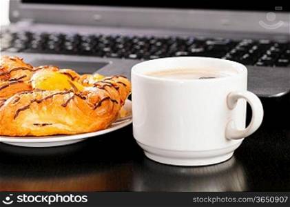laptop and cup of hot coffee on table