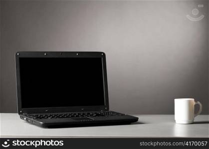 laptop and cup of hot coffee on table