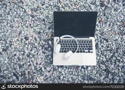 Laptop and Earphone on rock background with copy space and graphics design element for student collage. Education concept.