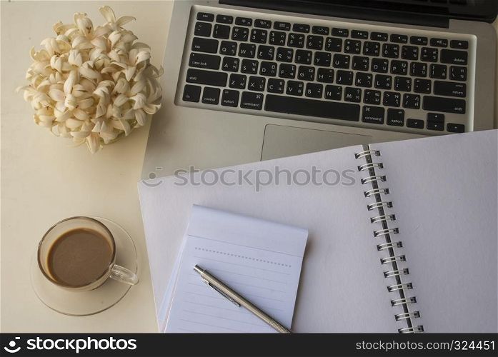 Laptop and flowers Notebooks and pens Scented candles on a white table that look relaxed