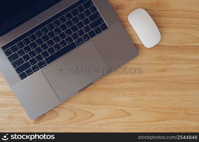 Laptop and mouse on wooden table top view with copy space.